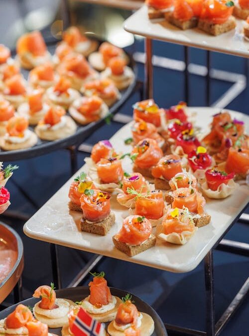 Plateaux de mini canapés salés avec saumon fumé sur toast et crème, décorations fraîches, lors d’un buffet.