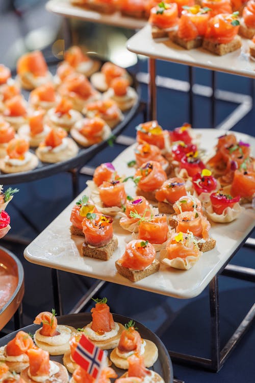 Plateaux de mini canapés salés avec saumon fumé sur toast et crème, décorations fraîches, lors d’un buffet.